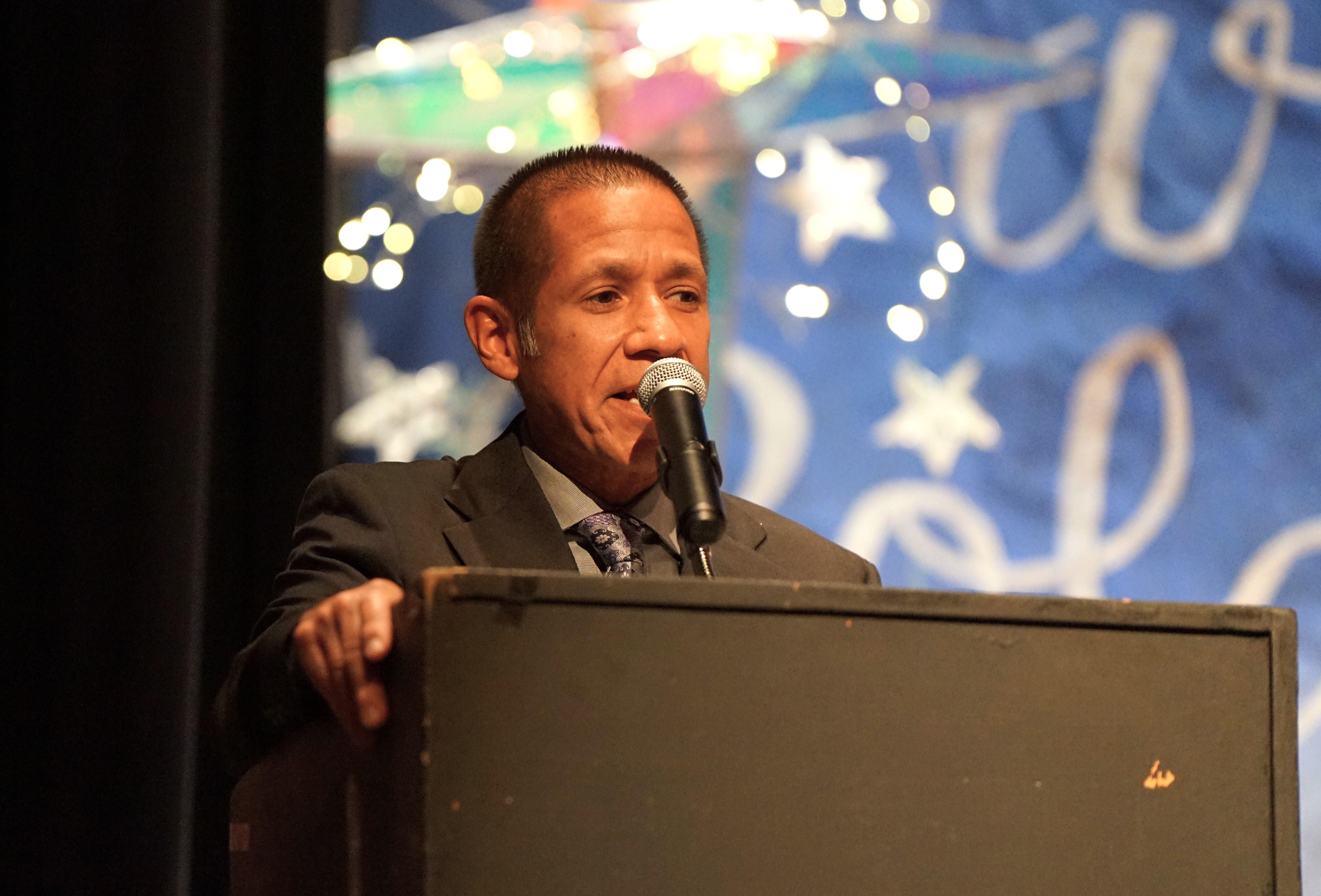 A man stands behind a podium and speaks into a microphone