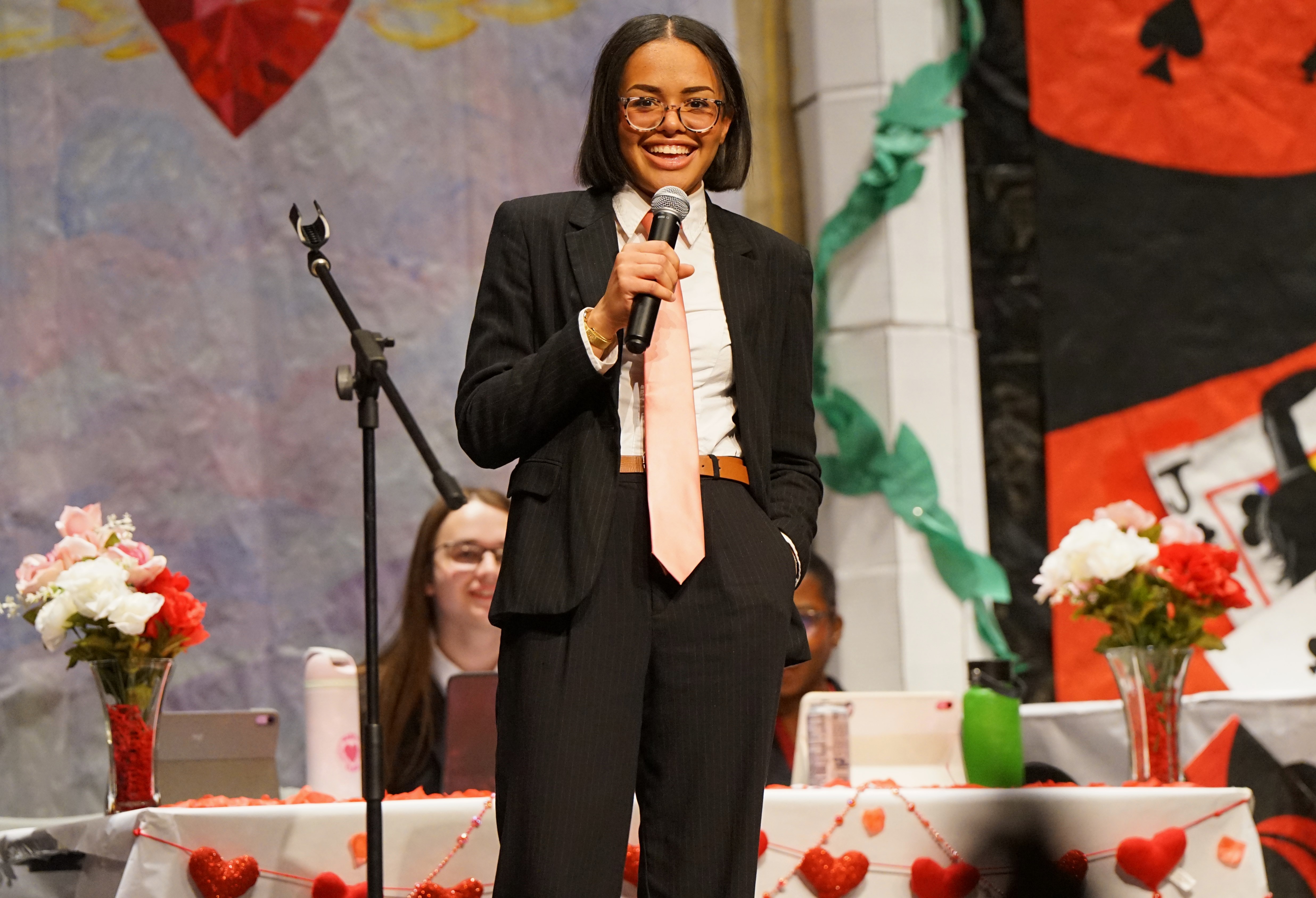 A girl smiles holding a microphone on stage