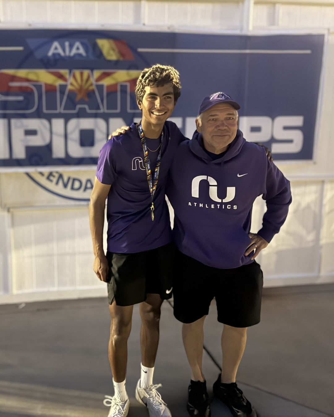 A teen boy poses with his tennis coach