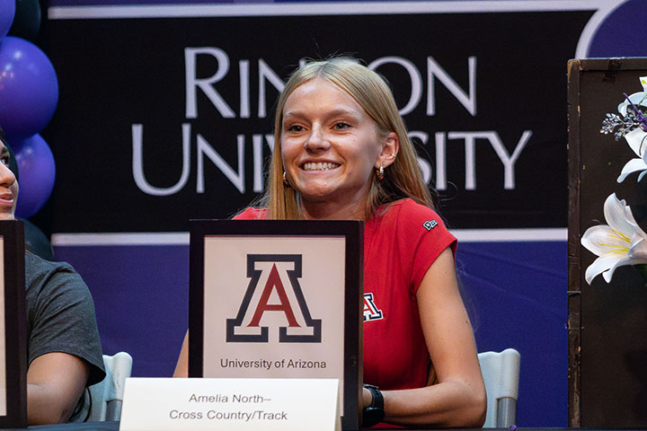 A teen girl smiles with her UofA letter of intent