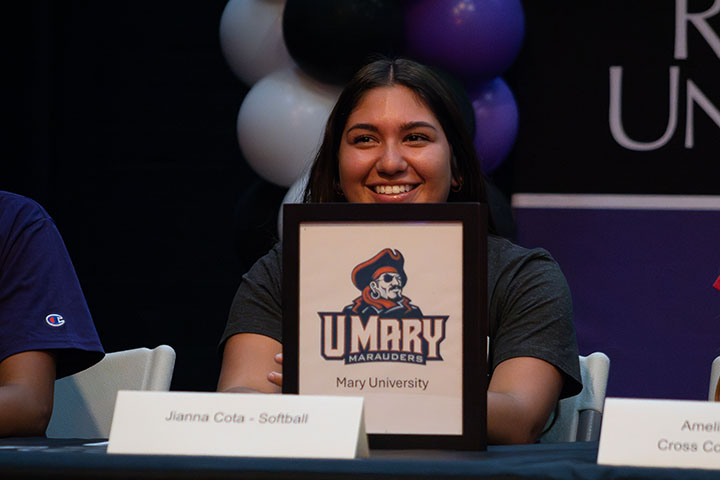 A teen girl smiles with her University of Mary letter of intent