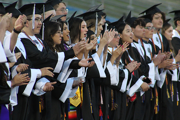 Graduates stand and clap during their ceremony