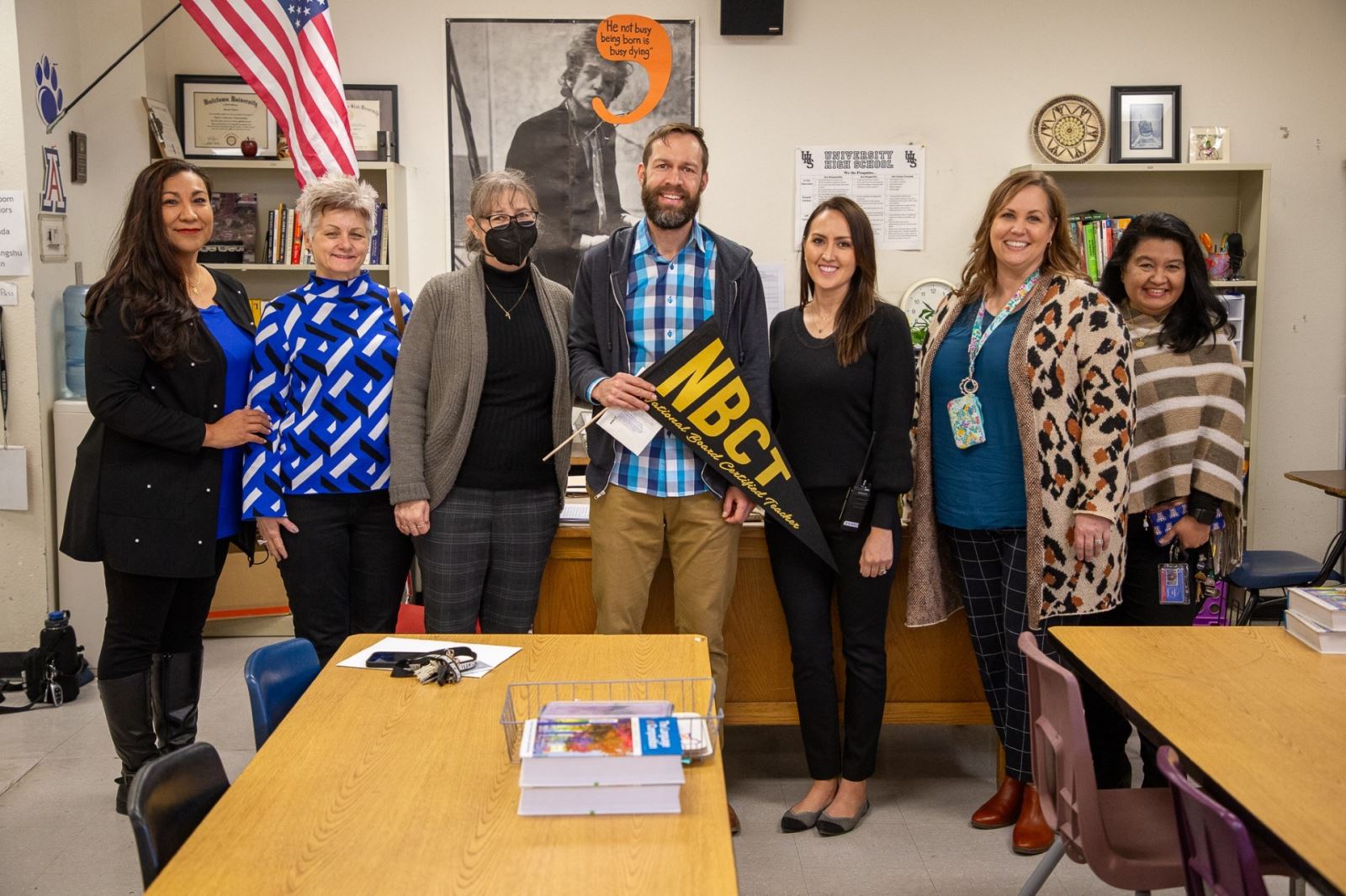 Mr. Hilbert smiles with his fellow staff members with his NBCT pennant.